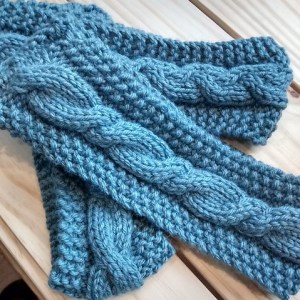 Three cable knit headbands in blue yarn. 